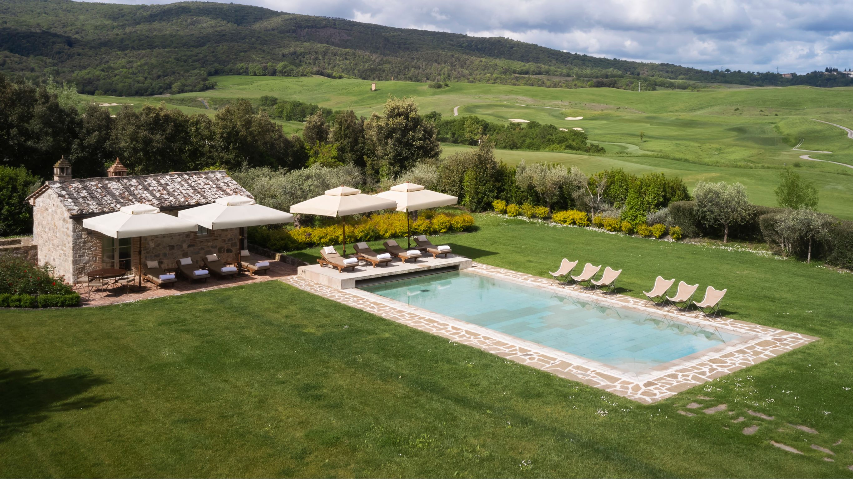 Outdoor pool area with lounge chairs and  white umbrellas